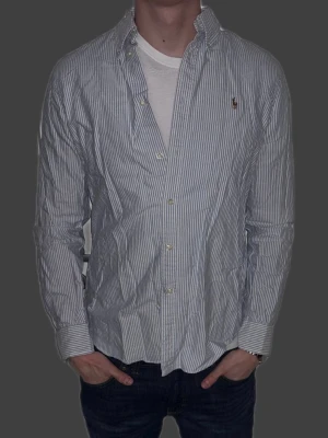 Blårandig skjorta från Ralph Lauren - Blårandig skjorta från Ralph Lauren i storlek L.  Fint skick till ett bra pris. Nypris: 1995kr. Mitt pris: 349kr. Vid frågor eller funderingar, tveka inte att höra av dig.