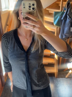 Randig blus med knytband - Snygg svart och grårandig blus med trekvartsärm och svart knytband i halsen. Från Kappahl i storlek   M 🌸  