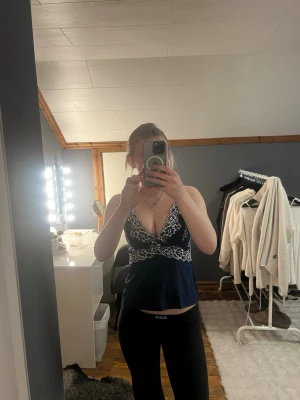 Mörkblå linne med vit spets - Mörkblå loungewear-linne med tunna axelband och v-ringning. Dekorerad med vit blommig spets över byst och midja. 