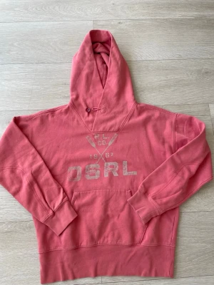 Hoodie från polo Ralph Laurent  - Snygg rosa hoodie från DS RL med tryck framtill och känguruficka. Klassisk modell med huva och ribbade muddar vid ärmslut och nederkant. Perfekt för en avslappnad och cool stil. Materialet känns mjukt och skönt mot huden. Storlek s inga defekter eller liknande hör av er vid frågor eller funderingar!