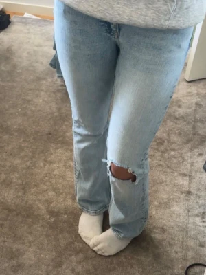 Ljusblå bootcut jeans med hål - Säljer ett par ljusblå bootcut jeans med ett snyggt hål på ena knät. Har gjort hålet själv jätte fin ljusblå färg på sista bilden ser man färgen bättre kom för fler frågor 