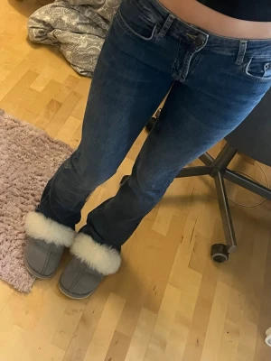 Mörkblå bootcut jeans - Snygga mörkblå bootcut jeans med klassisk femficksmodell och lägre midja. Jeansen har en lätt tvättad look och raka ben som går ut lite nedtill. Perfekta till sneakers eller boots för en avslappnad stil.