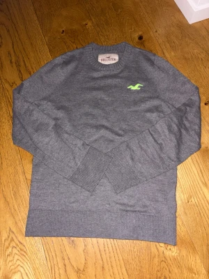 Grå hollister tröja - Riktigt fin hollister tröja med grönt märke. Stl m. Väldigt fint skick med inga defekter. Stilren hyfsat tunn stickad tröja. Sammanlagt en riktigt fin tröja 