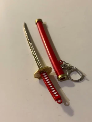 Keyring-JJK - Nyckelring i form av ett katana svärd med tillhörande slida. Perfekt för dig som gillar anime och manga.
