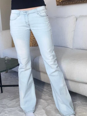 Ljusblå lågmidjade utsvängda jeans - Perfekta lågmidjade ljusblå jeans med bootcut och skit snygga detaljer både på fickorna fram och bak!💓 Midjemått 35cm Benlängd 80cm. Jag är 175cm lång och brukar ha midjemått 37/38cm. Någon sten har lossnat men annars toppen skick 
