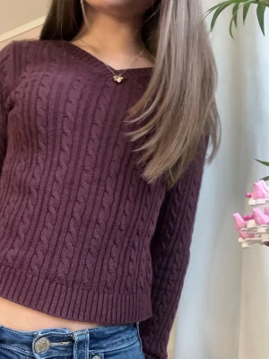 Vinröd kabelstickad tröja Hollister - Vinröd kabelstickad tröja från Hollister med v-ringning och långa ärmar. Tröjan har ribbade muddar och nederkant, samt ett klassiskt kabelmönster över hela plagget. Perfekt för lager-på-lager och snygg till jeans.