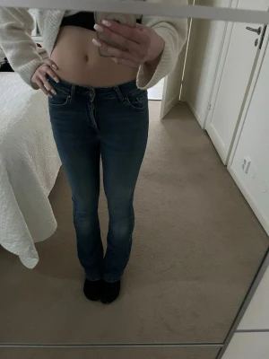 Blå bootcut jeans med låg midja - Snygga blå bootcut jeans med låg midja och klassiska fickor både fram och bak. Jeansen har en smal passform upptill och lätt utsvängda ben. Perfekta för en avslappnad och trendig look.