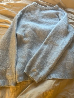 Ljusblå stickad tröja från BikBok - Mysig ljusblå stickad tröja från BikBok i en blandning av mohair och ull. Tröjan har rund halsringning, långa ärmar och ribbade muddar vid ärmslut och nederkant. Perfekt för kalla dagar och enkel att matcha med jeans eller kjol. Jag har använt den 2-3 ggr då jag inte tyckt om den jätte mycket på mig själv. Priset går att diskutera 