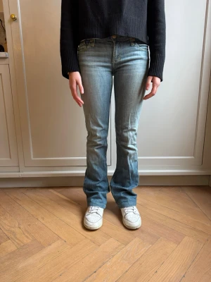 Ljusblå bootcut jeans från Rock & Republic jeans - Säljer ett par ljusblå bootcut jeans  med klassiska fem fickor och snygga slitningar. Jeansen har låg midja och subtila detaljer på bakfickorna. Perfekta för en avslappnad och trendig look.Rock & Republic jeans Storlek 25 Snygga Rock & Republic jeans i ljus mellanbla tvätt med tydlig R-logga pa baktickorna. Smickrande passtorm som formar sig fint över höfter och ben. Rak modell med lätt bootcut som ger en balanserad silhuett. Perfekta till både sneakers och klackar. 