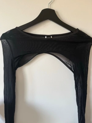 Svart mesh bolerotopp - Snygg svart bolerotopp i meshmaterial med lång ärm. Perfekt att styla över ett linne eller klänning för en trendig lager-på-lager-look. Tunn och genomskinlig för en edgy vibe.