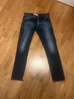 Richard J Brown Tokyo jeans - Snygga mörkblå slim fit jeans med tvättade och slitna detaljer på framsidan. Klassisk femficksmodell med knappgylf och raka ben. Storleken är 33 och märket är i samma prisklass som Jacob cohen och tramarossa och nypriset ligger på ca 4000kr