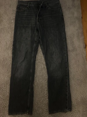 Weekday Space Relaxed Straight Jeans - Säljer ett par gråa jeans med rak passform och diskreta slitningar. Jeansen har klassisk femficksdesign och normal midja. Materialet är denim i bomull. Den sista bilden visar hur färgen är under starkt ljus/ blixt. Dom har tappat lite färg nere vid slutet av benen.