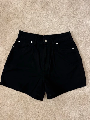 Svarta högmidjade shorts i bomull - Svarta shorts med hög midja och klassisk femficksdesign. Gjorda i mjuk bomull med knapp och dragkedja framtill. 