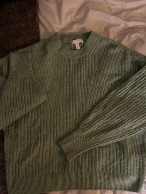 Ljusgrön ribbstickad tröja från H&M - Mysig ljusgrön stickad tröja från H&M med ribbstickat mönster. Tröjan har rund halsringning, långa ärmar och breda muddar vid ärmslut och nederkant. Perfekt för lager-på-lager och chill dagar.