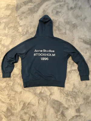 Blå hoodie från Acne Studios -  Perfekt för en avslappnad och stilren look.kan sitta lite större men borde ännu passa dig med medium
