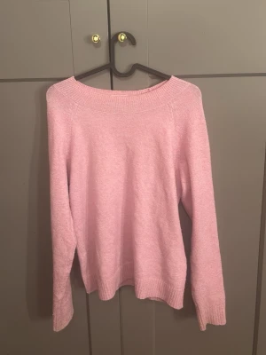 Ljusrosa stickad tröja - Mysig ljusrosa stickad tröja med rund halsringning och långa ärmar. Tröjan har ribbade muddar vid hals, ärmslut och nederkant. Perfekt för att hålla värmen under kyliga dagar och enkel att matcha med olika outfits.