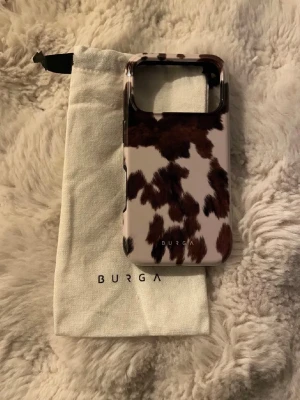 BURGA mobilskal brun leopardmönster ( nypris är 629kr) - Snyggt mobilskal från BURGA med trendigt leopardmönster i brunt och svart på vit botten. Skalets utsida är glansig och insidan är svart och matt. Tillverkat i tålig plast och levereras med en vit tygpåse med BURGA-logga.