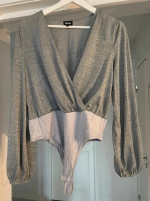 Grå glittrig body med omlott - Snygg grå/silvrig glittrig body med ’öppen’ ärm.