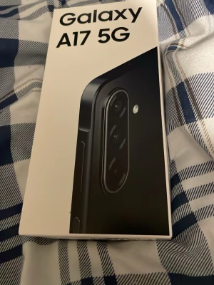 Samsung Galaxy A17 5G smartphone - Samsung Galaxy A17 5G är en modern mobiltelefon med stilren svart design och rundade kanter. Telefonen har flera kameror på baksidan och levereras i originalförpackning. Perfekt för dig som vill ha snabb 5G-uppkoppling och en snygg, pålitlig lur. Helt oöppnad och 128gb och 12 månaders garanti 