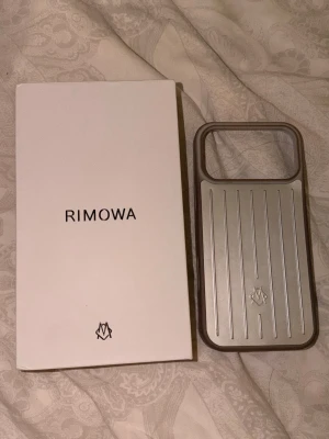 Rimowa silver mobilskal aluminium - Snyggt mobilskal från Rimowa i silverfärgad aluminium med klassiska räfflade linjer och logga på baksidan. Skalets kanter blev lite bruna pga användning. Det är inte i bra skick därför priset. 