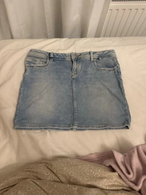 Ljusblå jeanskjol från LTB - Trendig ljusblå jeanskjol från LTB med klassisk femficksdesign och bälteshällor. Kjolen har en rak, kort passform och är tillverkad i mjuk denim. Perfekt att matcha med en enkel t-shirt eller hoodie för en avslappnad look. Säljer då jag köpte fel storlek❣️