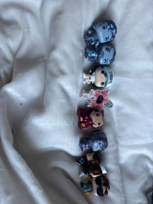 Samling Funko Pop-nyckelringar - Säljer en samling med sju Funko Pop-nyckelringar i olika färger och former. Figurerna är inspirerade av populärkultur och har detaljerade ansikten och kläder. Perfekt för dig som gillar att samla eller vill ha coola accessoarer till nycklarna.