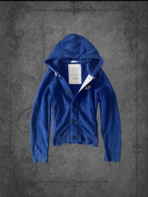 Abercrombie & Fitch cardigan ( 2000’s modell ) - Sjukt eftertraktad Abercrombie & Fitch cardigan i blå – stl L. Stilren och populär modell som är svår att få tag på i denna färg och storlek. Blå färg som är lätt att matcha och alltid funkar.  • Storlek: L • Skick: Väldigt bra • Färg: Blå • Original & hög kvalitet  Varför den är eftertraktad: – Populär Abercrombie & Fitch-modell – Snygg och lättmatchad blå färg – Svår att hitta i fint skick – Säljs snabbt när de dyker upp  Skriv vid intresse eller för snabb affär✌️ Skickas inom 24h 📦