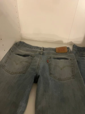 Ljusblå Levi's jeans med raka ben - Säljer ett par klassiska ljusblå jeans från Levi's med raka ben och femficksmodell. Jeansen har en ikonisk läderpatch bak i midjan och den röda Levi's-taggen på bakfickan. Perfekta för en avslappnad och tidlös stil.