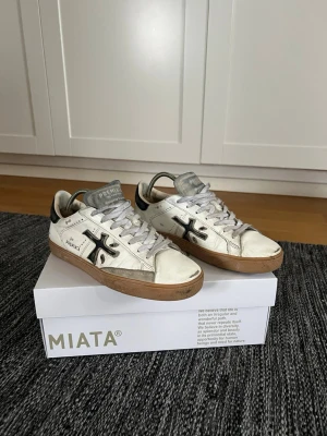 Premiata vita sneakers med svart detalj - Snygga vita sneakers från Premiata med svart logga på sidan och svarta detaljer vid hälen. Samt svart sula. Skobox medkommer.                   Blå avfärgning på tungan. Nypris 3000 kr