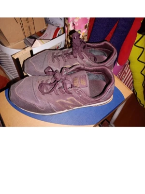 Vinröda New Balance 373 sneakers - Snygga vinröda New Balance 373 sneakers med klassisk design. Skorna har ovandel i mocka och textil, snörning och en diskret logga på sidan. Perfekta för dig som gillar en stilren och sportig look.