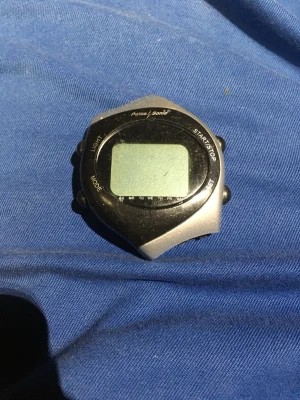 Pulsmätare med bröstband Garmin - Pulsmätare från Garmin med svart bröstband och digital display. Bröstbandet är justerbart och har inbyggda sensorer för exakt pulsmätning. Displayen är svart och silverfärgad med knappar för olika funktioner. Perfekt för träning och kondition.