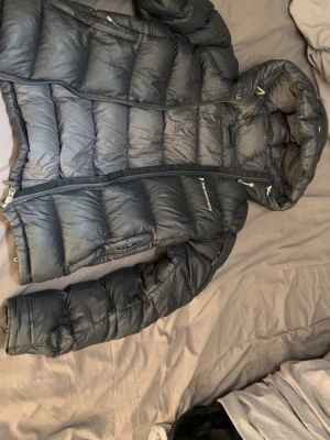 Svart dunjacka från Peak Performance - Snygg svart dunjacka från Peak Performance i storlek XS. Dragkedjan är trasig (funkar ibland om man lyckas dra upp den rätt) köpt på Vinted men gillar inte hur den sitter på mig. Förutom dragkedjan så är jackan i bra skick, inga hål eller andra skavanker som jag har sätt. Bara att höra av sig om man undrar något, pris kan förhandlas