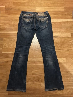 Mörkblå bootcut miss me jeans - Säljer ett par mörkblå bootcut jeans från Miss Me med snygga broderade detaljer och nitar på bakfickorna. Jeansen är i strl 27 och passar mig som är ca 160 cm lång. Hör av er för bilder på eller mått!❤️Priset är absolut diskuterbart så hör av er vid funderingar🫰🏼