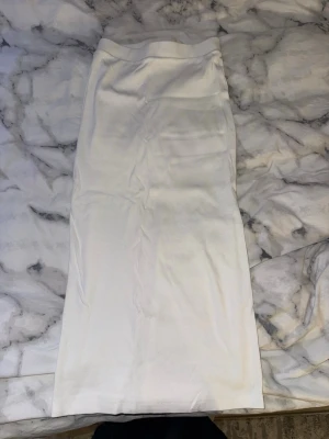 Vit långkjol i ribbad bomull från Zara - Säljer en enkel och stilren vit långkjol i ribbad bomull. Kjolen har en rak passform och är perfekt för dig som gillar minimalistisk stil. Passar till många olika outfits och är superenkel att matcha.