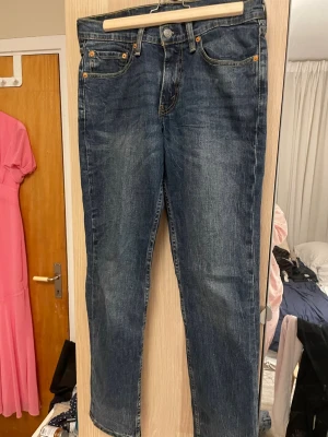 Levi's raka blå jeans - Klassiska blå jeans från Levi's med rak passform och fem fickor. Jeansen har en snygg tvättad look och detaljer i kopparfärgad metall. Tillverkade i slitstark denim med Levi's ikoniska läderpatch bak i midjan.