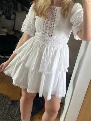 Studentklänning vit - Fin vit studentklänning från Gina Tricot med brodering och volanger. Funkar även bra till sommartillställningar eller liknande. Endast använd en gång. 