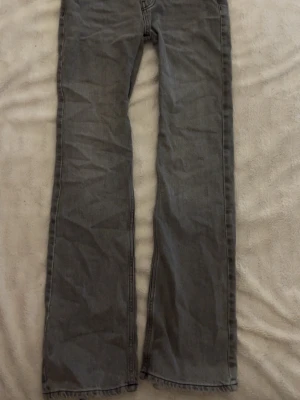 gråa raka jeans med dragkedja - Säljer ett par gråa jeans med rak passform och klassisk femficksdesign. Jeansen har dragkedjegylf, bälteshällor och är tillverkade i denim. Perfekta för en avslappnad och stilren look. Jeansen har blivit omsydda till lågmidjade