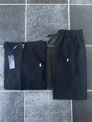 Svart Ralph lauren tracksuit - Svart Ralph lauren tracksuit. Ziptröja med luva samt fickor och snören för maximal bekvämlighet. Mjukisbyxor med fickor på sidorna, perfekt för en chill dag. På insidan står det storlek L men passar som S-M (175-183cm) beroende på kroppsbyggnad. Pris kan diskuteras!!
