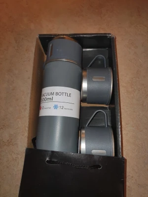 Grå termosflaska med två muggar - Säljer en grå vakuumflaska på 500 ml tillsammans med två matchande muggar. Flaskan håller drycken varm eller kall i upp till 12 timmar. Setet har en modern design med silverfärgade detaljer och är tillverkat i rostfritt stål och plast. Helt nytt 