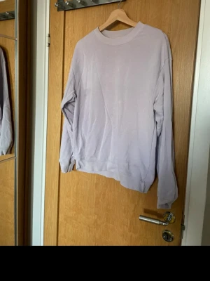 Ljuslila sweatshirt från Monki - En stilren ljuslila sweatshirt från Monki i storlek S. Tröjan har rund halsringning, långa ärmar och ribbade muddar vid ärmslut och nederkant. 