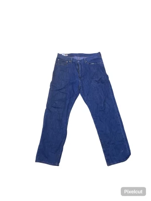 Blå raka jeans från Levi's - Klassiska blå jeans från Levi's med rak passform och fem fickor. Jeansen har en ikonisk läderpatch bak i midjan och är gjorda i slitstark denim. Perfekta för en avslappnad och tidlös stil.