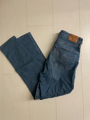 Blå raka jeans från Levi's - Klassiska blå jeans från Levi's med rak passform och femficksdesign. Jeansen har en brun läderpatch bak i midjan och den ikoniska röda Levi's-taggen på bakfickan. Tillverkade i slitstark denim med snygg tvättad look.