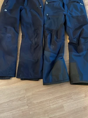 Mörkblå täckbyxor från 8848 Altitude - Säljer ett par mörkblå täckbyxor från 8848 Altitude. Byxorna har dragkedjefickor, förstärkta partier vid knän och benslut samt justerbar midja. Perfekta för vinterns alla äventyr i snön och håller dig varm och torr.