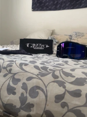 Raven svarta sportiga glasögon - Säljer ett par sportiga glasögon från Raven med bred svart båge och spegelblått glas. Perfekta för dig som vill ha en cool och skyddande look. Kommer med originalförpackning.