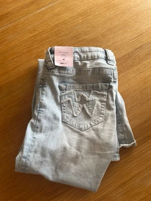 Ljusblå jeans från Gina Tricot - Snygga ljusblå jeans från Gina Tricot med klassisk femficksdesign och broderad bakficka. Jeansen har normal midja och utsvängda ben, perfekta för en avslappnad och trendig look. Tillverkade i mjukt denimtyg som är skönt att bära hela dagen. Jensen är helt nya och aldrig andvända, en av lapparna är kvar. Skriv för fler bilder eller frågor!🥰