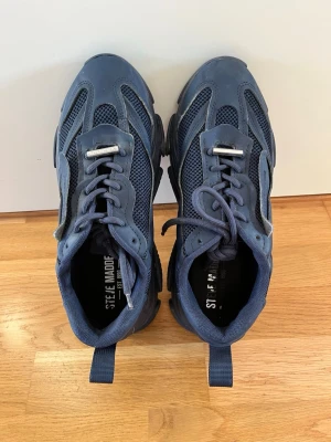 Blå sneakers från Steve Madden - Snygga blå sneakers från Steve Madden med chunky sula och meshdetaljer för extra ventilation. Skorna har en sportig design med coola paneler och dragflik bak. Perfekta för dig som gillar streetstyle och vill sticka ut med dina skor.