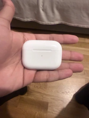 Apple AirPods Pro laddningsetui - Säljer ett par Apple AirPods Pro med det klassiska vita laddningsetuiet i blank plast. Etuiet är kompakt och har en rundad, rektangulär form med magnetlock. Perfekt för dig som vill ha trådlösa in-ear hörlurar med snygg och stilren design.