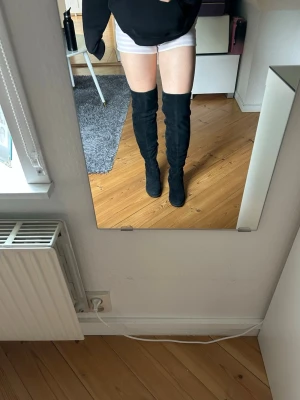 Svarta overknee stövlar i mockaimitation - Säljer ett par svarta overknee stövlar i mjuk mockaimitation. De har rund tå, låg klack och sitter tight längs benet för en snygg siluett. 