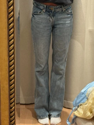 Ljusblå bootcut jeans - Säljer ett par ljusblå bootcut jeans med klassisk femficksdesign och normal midja. Lite fransiga där nere