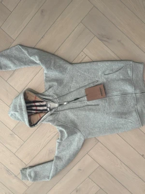 Randig hoodie från Burberry - Säljer en snygg hoodie från Burberry med klassiska breda ränder i svart och vitt.  har en modern och stilren look, perfekt för dig som gillar exklusiva märken och tidlös design. Märkeslapp och etikett från Burberry London England medföljer.